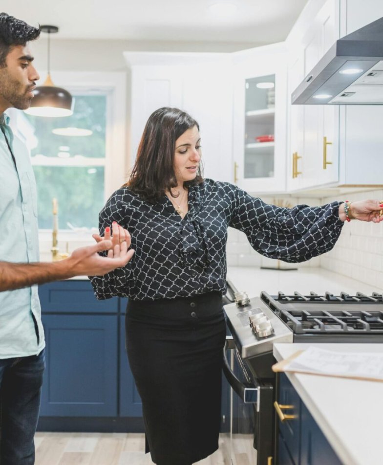 Real estate agent showing a modern kitchen interior with brass fixtures to a client.